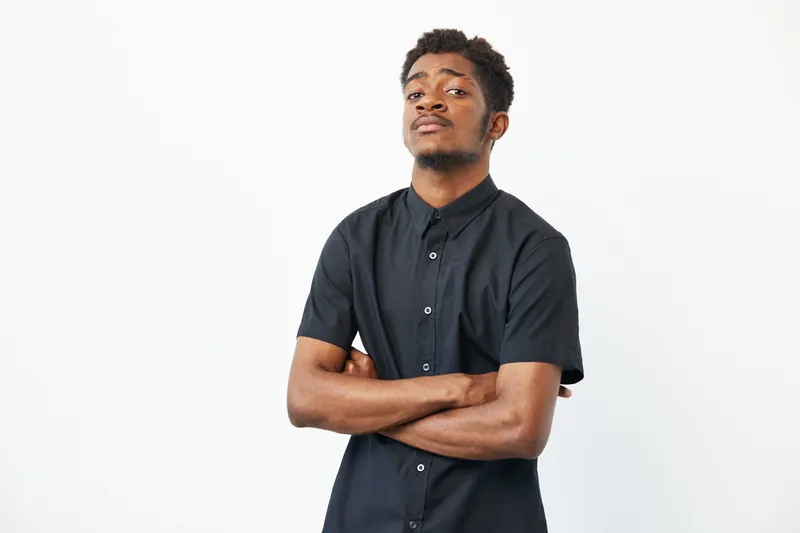 Confident black man posing with crossed arms, showcasing style and determination. His strong presence adds character to any project or campaign.