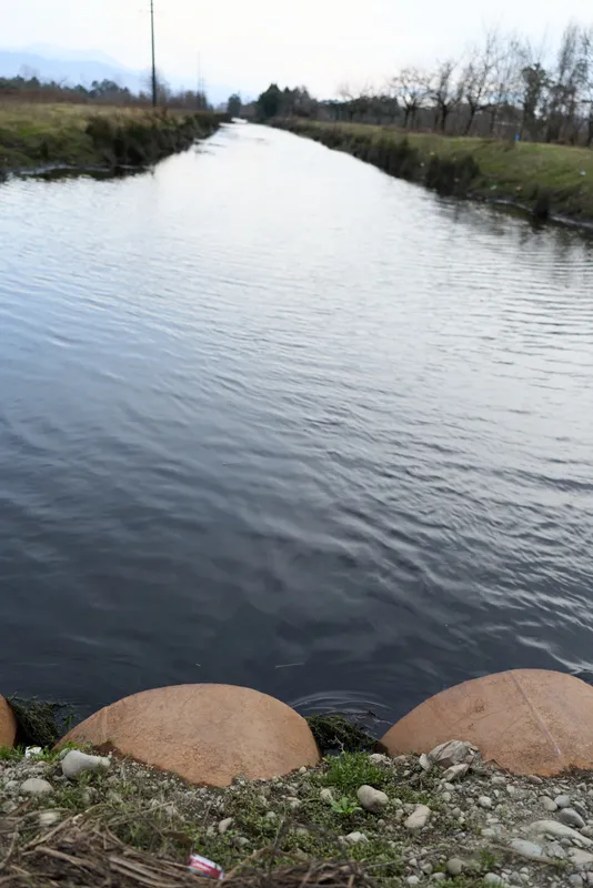 River stream water outdoors nature landscape with rocks and shoreline stones, calm current and gentle ripples, overcast sky, rural bank scenery, quiet mood, natural colors