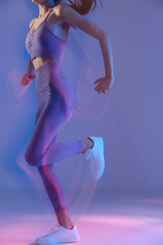woman sport fitness wearing purple activewear running indoors with dynamic motion blur and vibrant blue and pink lighting, athletic lifestyle concept