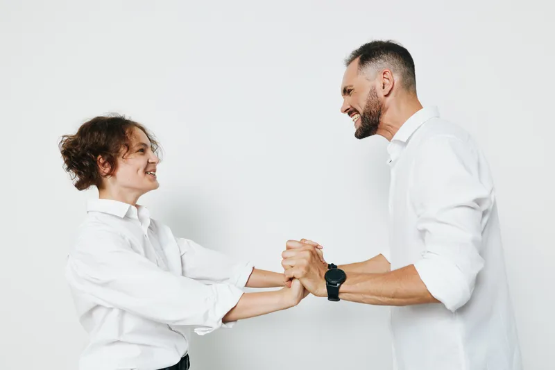 A professional man and colleague celebrate success with a fistbump against a solid colored background, showcasing teamwork, confidence, and positive business energy.
