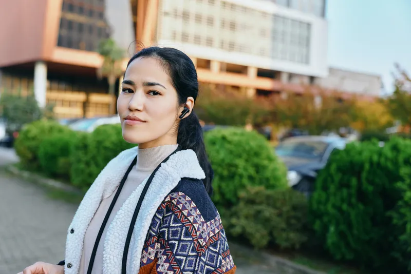 Woman wearing a patterned cardigan and shearling coat outside in a street setting, casual fashion, natural light, candid style, autumn mood and calm confidence
