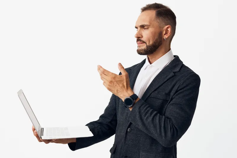 A professional man stands with a laptop, exuding confident focus against a solid colored background, inviting trust and future oriented business insight.