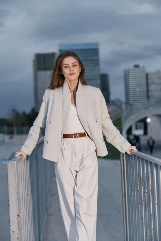 Professional woman in stylish business attire poses confidently against an urban backdrop, showcasing elegance and modernity in a dynamic city setting.
