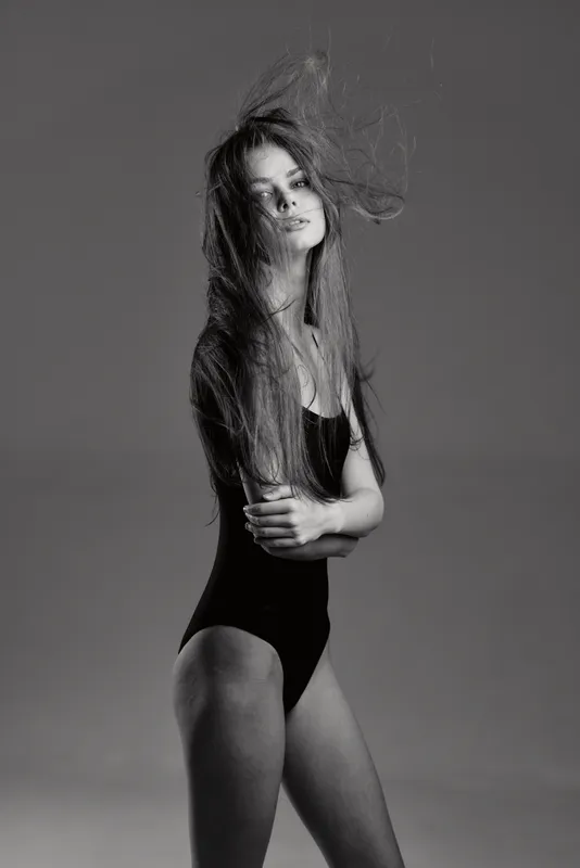 Black and white portrait of a young woman with long hair in a swimsuit with serious expression and dramatic lighting