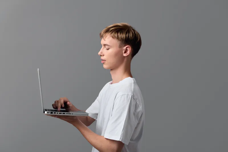 Young student side view typing on a laptop with focus education technology learning casual remote study online courses and screen modern setup for digital tasks and study