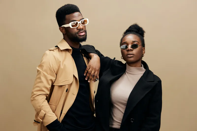 Stylish young couple posing elegantly against a neutral background, showcasing modern fashion with trendy accessories and confident expressions, ideal for fashion campaigns