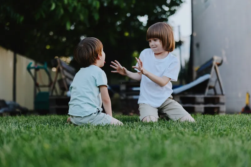 Playful children enjoying a sunny day outdoors, capturing the joy of childhood and friendship in a vibrant green garden setting.