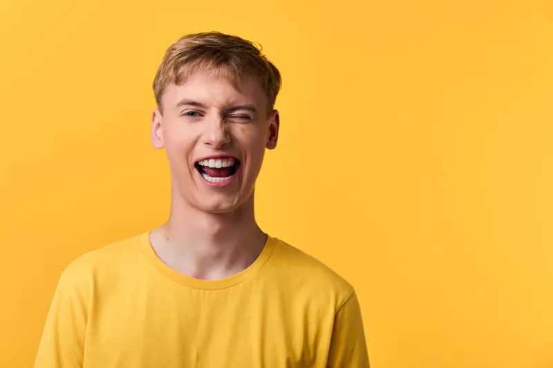 Laughing man in a bright yellow shirt against a matching yellow backdrop, conveying joy, energy and a cheerful mood for lifestyle, advertising and happy branding visuals.