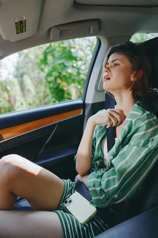 Car, woman, relaxed mood, a woman sits in a car seat wearing a green striped shirt, seatbelt fastened, natural light, reflective moment, ready for a journey ahead.