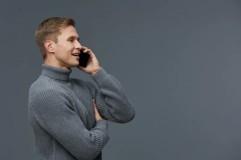 smiling man talking phone wear gray knitted sweater stand on dark gray background digital nomad remote communication concept