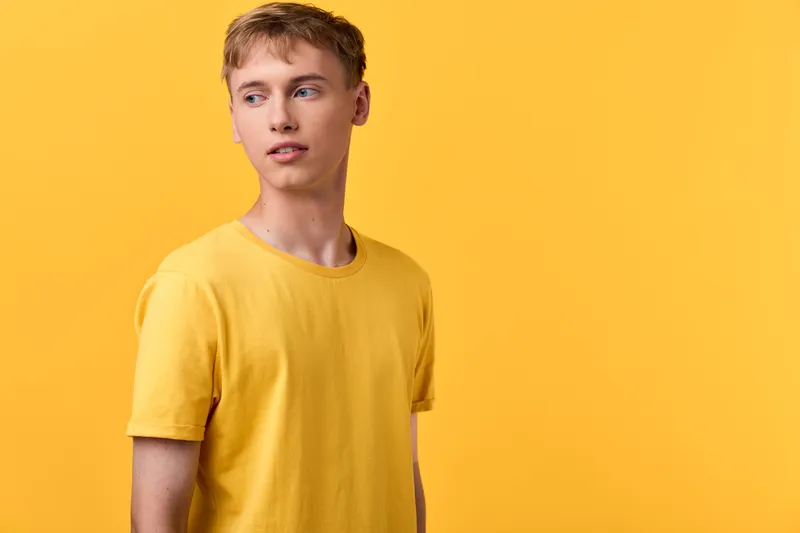 Yellow shirted man stands against a bright yellow backdrop in a clean studio, casual fashion styling, vibrant color coordination, confident expression, minimalist lifestyle image