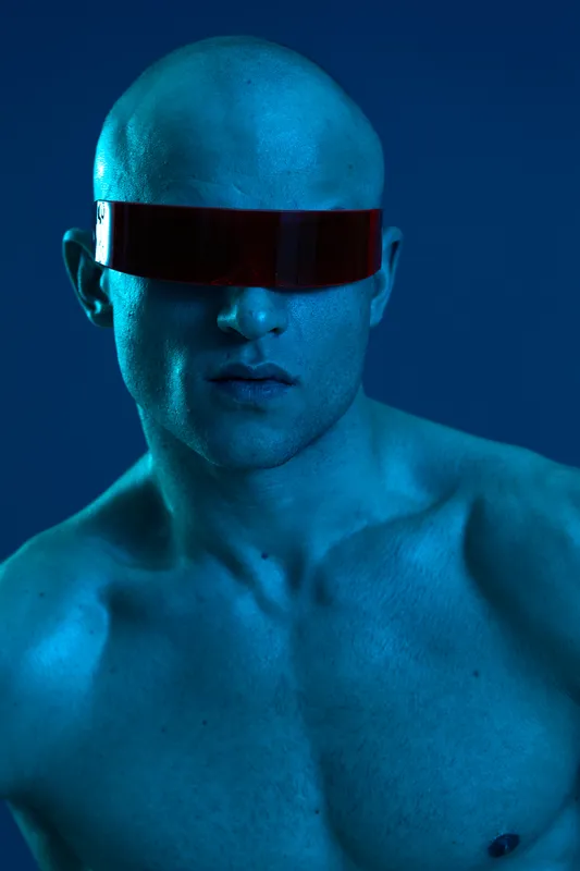 Futuristic man with bold appearance, highlighting striking blue tones and dynamic lighting effects. Captivating and visually unique presentation.