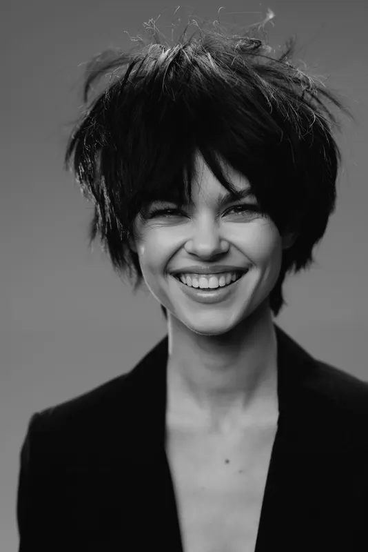 smiling woman with short hair in black and white portrait, joyful expression, studio background