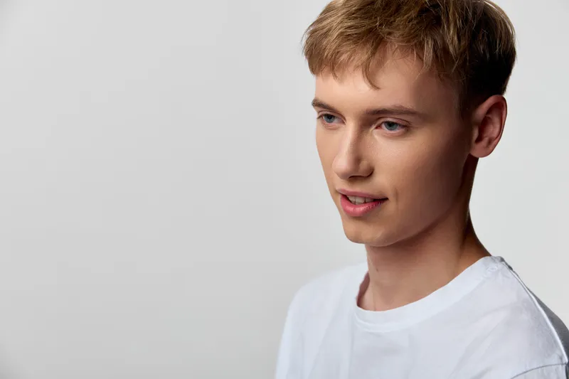 Young man in a white t-shirt, studio head and shoulders shot, calm expression, soft lighting, neutral background, casual mood, modern lifestyle concept
