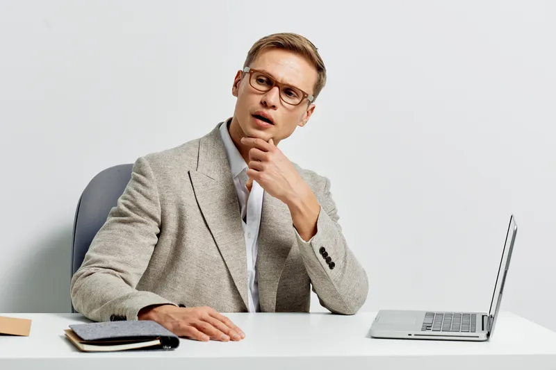 young man working digital nomad style wear glasses gray blazer thoughtful look at laptop use voice assistant technology isolated white background