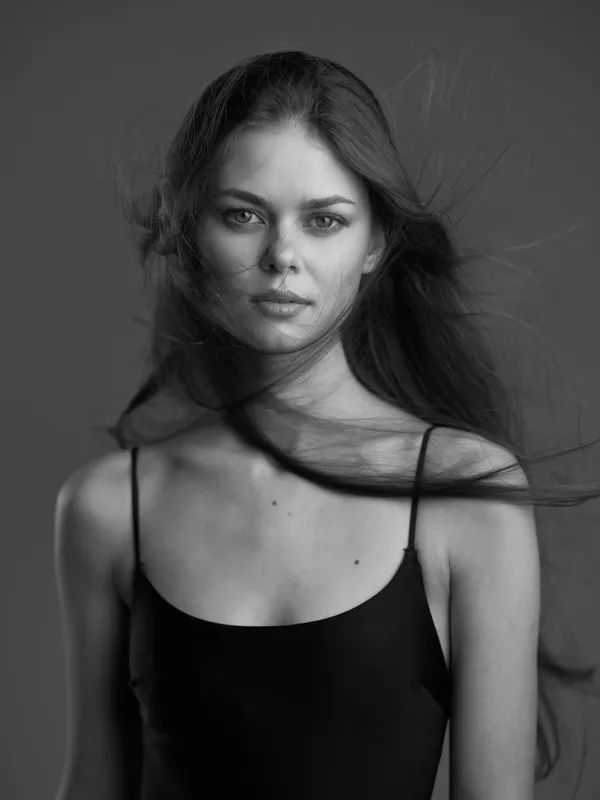 Black and white portrait of a young woman with long hair and serious expression wearing a black top.