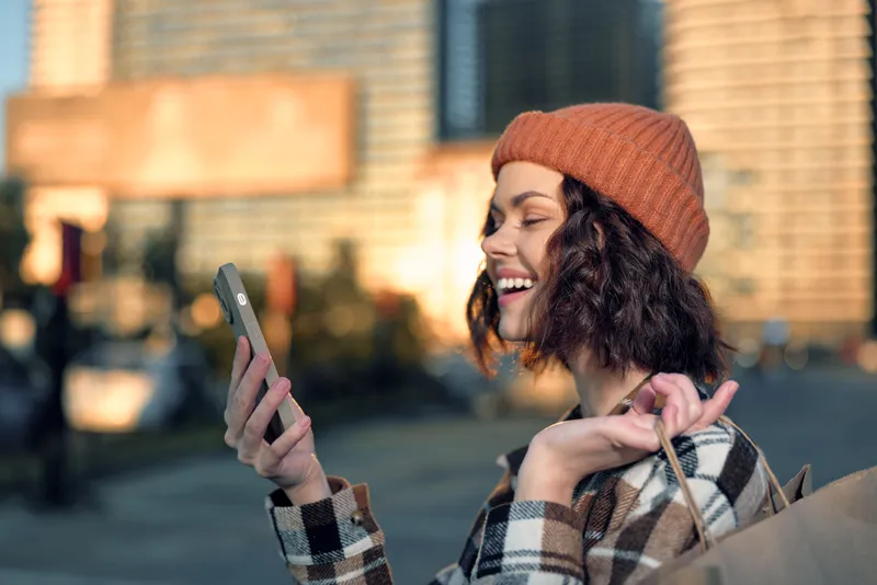 woman smile smartphone shopping urban portrait city candid moment showing authenticity, candid lifestyle and golden hour glow, mindful living and emotional storytelling in modern street scene
