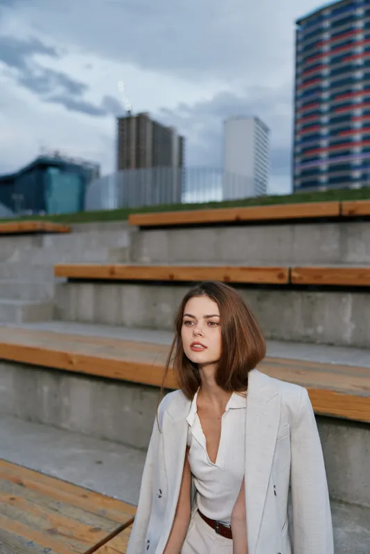 Businesswoman in a stylish outfit poses confidently outdoors, showcasing modern professional attire amidst an urban backdrop with sleek architecture.