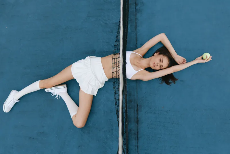 Young woman in sportswear stretching on a tennis court, showcasing athleticism, grace, and determination in a vibrant and dynamic setting
