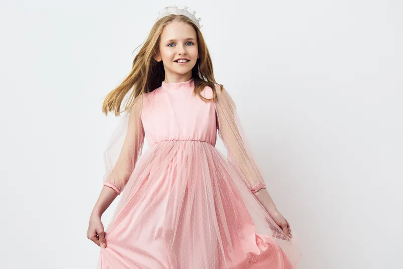 Charming young girl in a pink dress, radiating joy and innocence while posing against a light background, perfect for spring themed designs and children s fashion