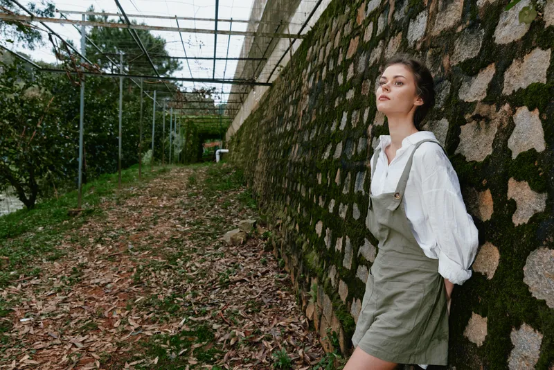 Young diverse model in casual green outfit expressing tranquility in a lush outdoor setting, showcasing nature s beauty and seasonal harmony