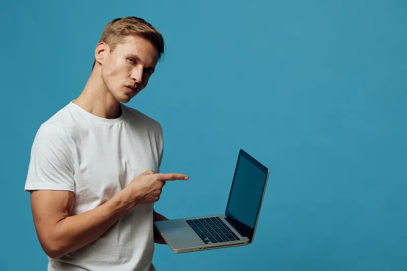 young caucasian man holding laptop use for digital nomad work remote freelance casual wear blue background
