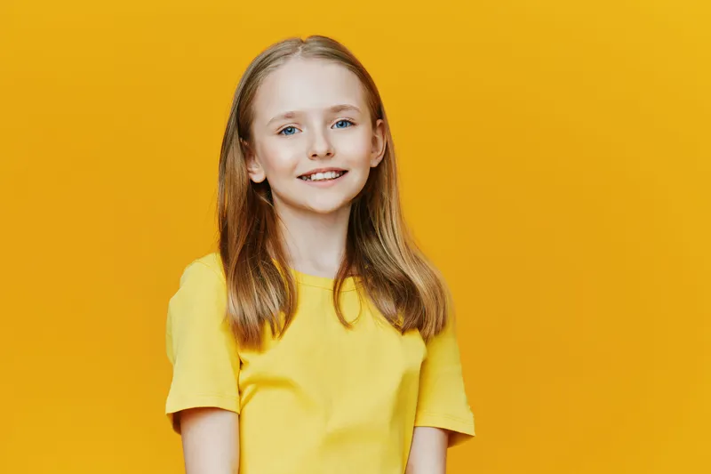Cheerful girl in a yellow t shirt smiling against a vibrant yellow background, embodying joy, youth, and positivity in a seasonal, bright, and uplifting concept
