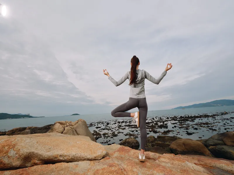 Young woman practicing yoga on rocky shore, peaceful emotion, active lifestyle, serene background, fitness, nature connection, healthy living