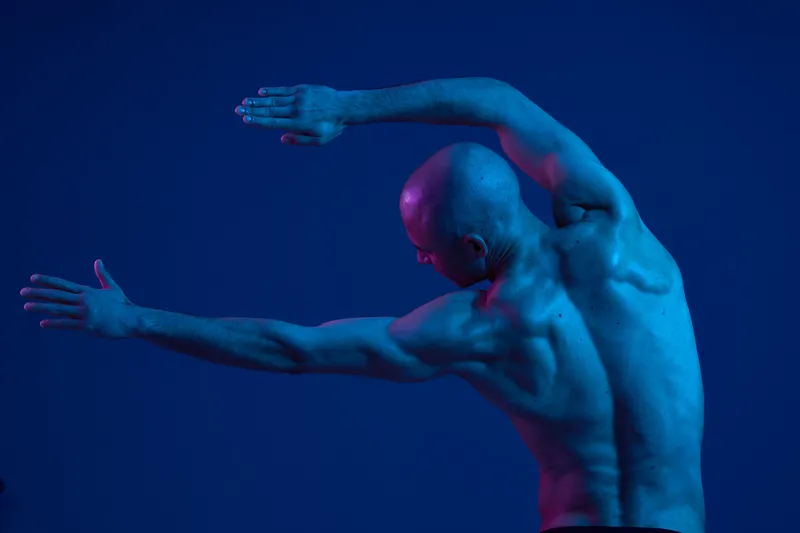 Athletic man demonstrating strength and flexibility with dynamic poses, emphasizing physical fitness and body movement in a stunning light setting.