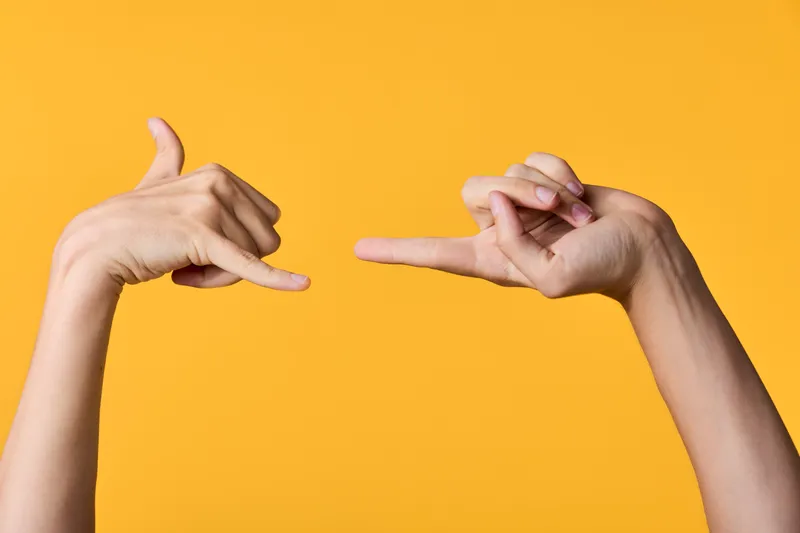 Hands frame a bright yellow backdrop, creating a bold gesture and artistic framing that highlights clean composition and creative photography for stock use.