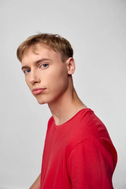 Young man wearing a red shirt in a studio shot with a neutral background, casual clothing and a calm, confident pose suitable for fashion, lifestyle and model catalog visuals