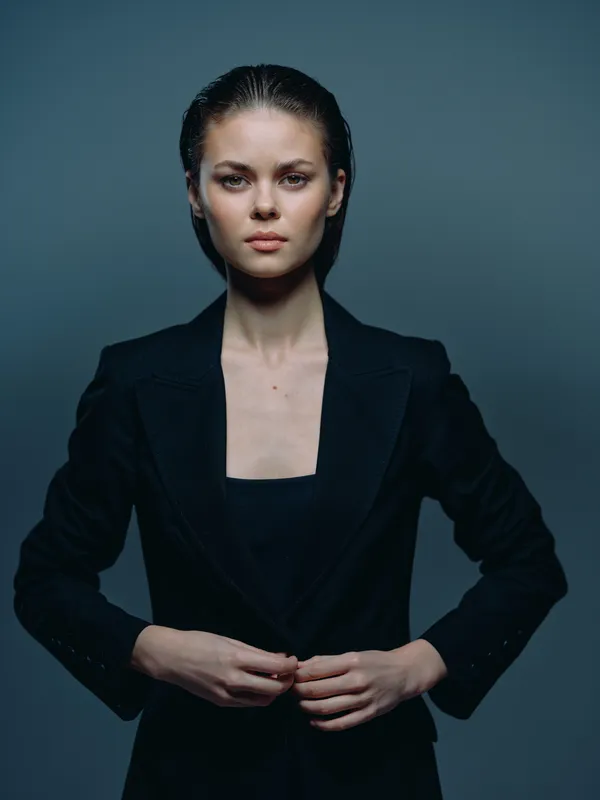 serious woman in black jacket with confident expression on dark background