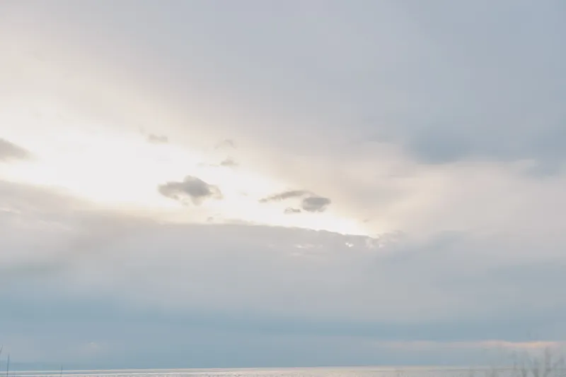 Calm ocean under cloudy sky during daytime. Soft light reflects on the water creating serene and peaceful mood. Concept for nature, landscape, and weather background.