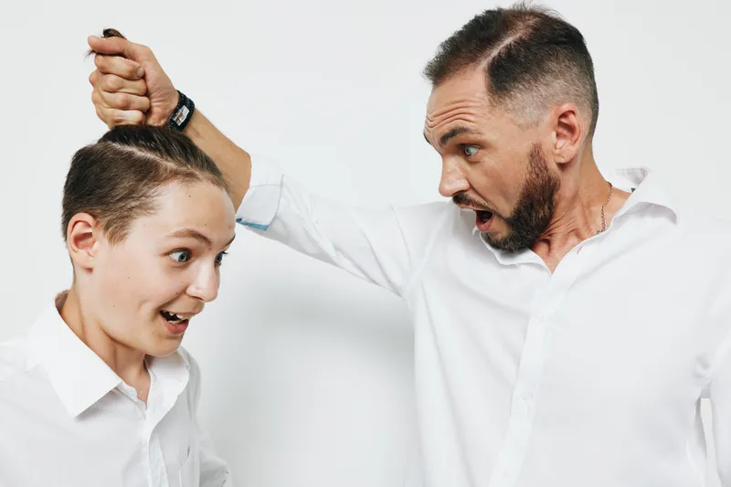 A professional man on an isolated colored background shows intense emotion during a business moment, suggesting confrontation, stress, and assertiveness in a workplace scene.