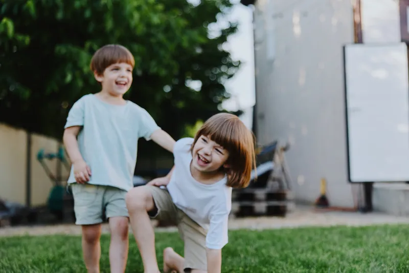Happy children playing outdoors, enjoying a sunny day while laughing and playing in a grassy backyard, capturing the essence of childhood joy.