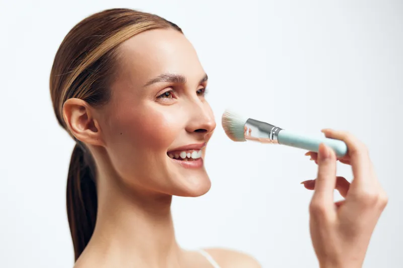 Cheerful female woman singing into microphone in a studio closeup portrait, smiling with pop vocal performance, against clean white background, soft lighting, focus on music audio