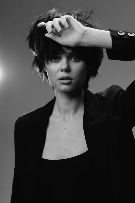 Black and white portrait of a young woman with short hair wearing a suit jacket and thoughtful expression