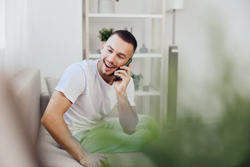 A man enjoying an emotional phone call, reflecting a blend of vulnerability and authentic connection. The image evokes modern feelings of mental health and therapy culture.