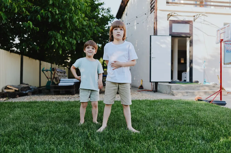Two boys standing together on a grassy lawn, showcasing youthful energy and playfulness. Their innocent expressions reflect a carefree summer day filled with joy.