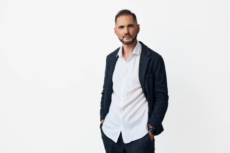 Portrait of a professional businessman in smart attire, standing confidently against an isolated colored background. His expression conveys calm focus, determination, and approachable leadership.