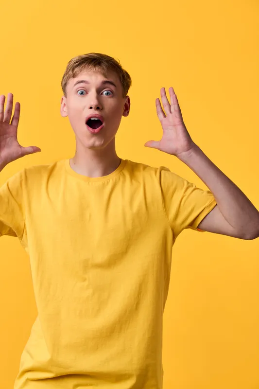 Surprise, astonishment, yellow shirt, man expression, evokes energy and fashion vibe in studio setup with bright background, casual clothing and openmouth pose, conveys vivid color and upbeat mood