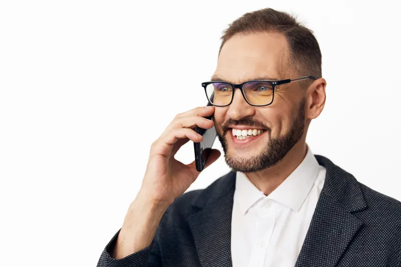 A professional business man on an isolated colored background, speaking on a mobile phone with a confident smile, expressing focus, leadership, and positive emotion.