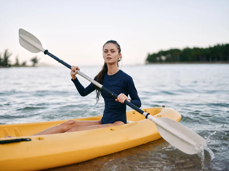 young woman kayaking in calm water with paddle during daytime outdoor activity in nature