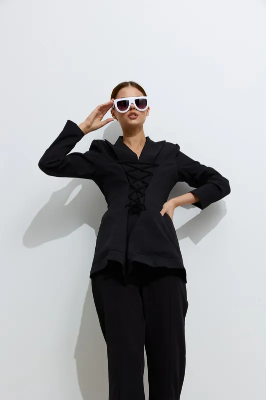 fashion woman in black outfit wears white sunglasses posing confidently against white background, stylish look, modern minimalism, trendy clothing