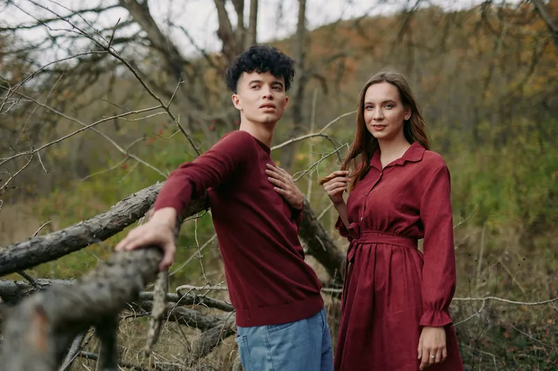 A young couple in a natural woodland setting, sharing an authentic moment of connection and genuine expression, captured with natural light and credible, unposed composition for lifestyle imagery.
