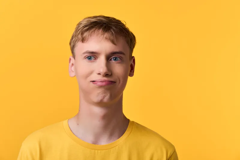 Yellow shirted man with a subtle smile against a bright yellow backdrop, studio shot conveying casual style, optimism and clean lifestyle imagery for fashion or product showcase
