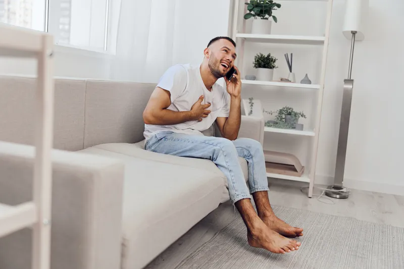 Happy man on the phone, expressing emotions during a heartfelt conversation in a cozy home environment, emphasizing connection and vulnerability in daily life.