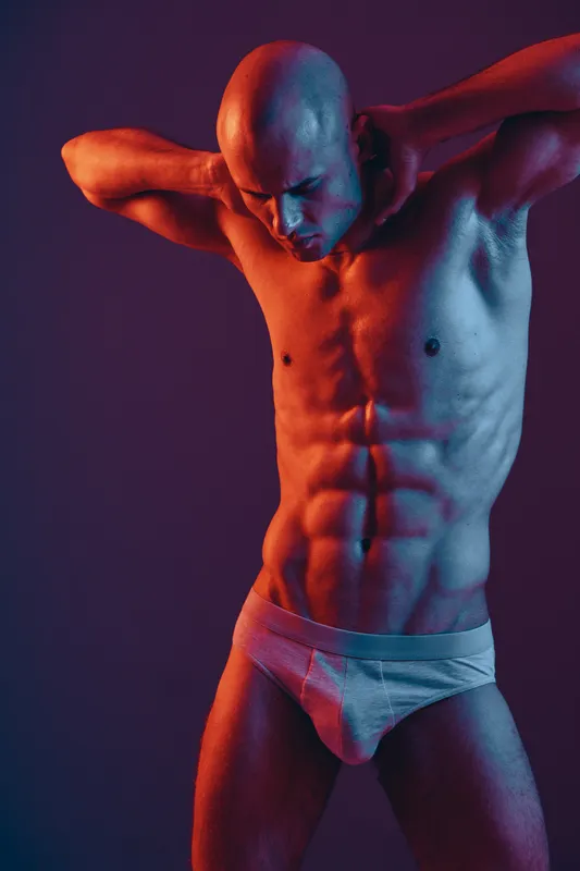 Fit man posing against a vibrant, multicolored backdrop, showcasing strength and determination. The image's bold colors highlight his athletic physique.