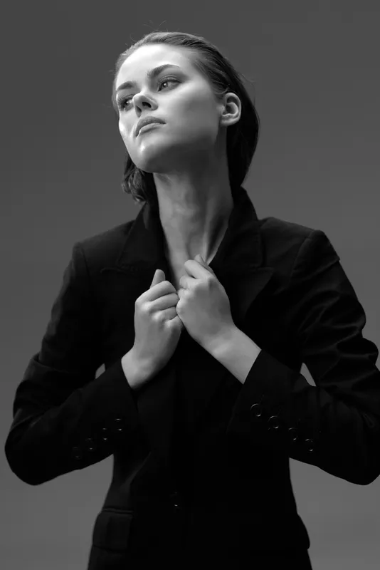 Black and white portrait of a confident woman in a dark blazer with a serious expression and stylish look