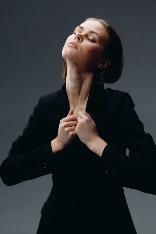 elegant woman in black jacket with closed eyes expressing calmness and grace in studio lighting